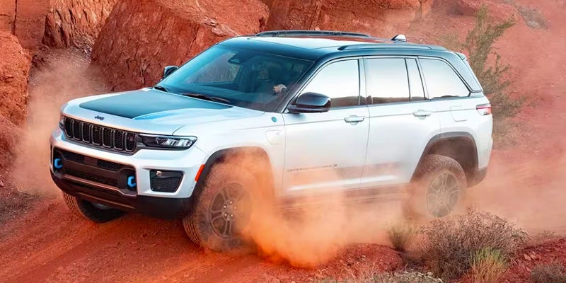 A white Jeep Grand Chrokee kicking up dust as it blazes a trail in the desert